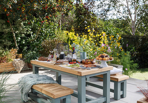 Outdoor table with a summer platter in a blooming floral garden