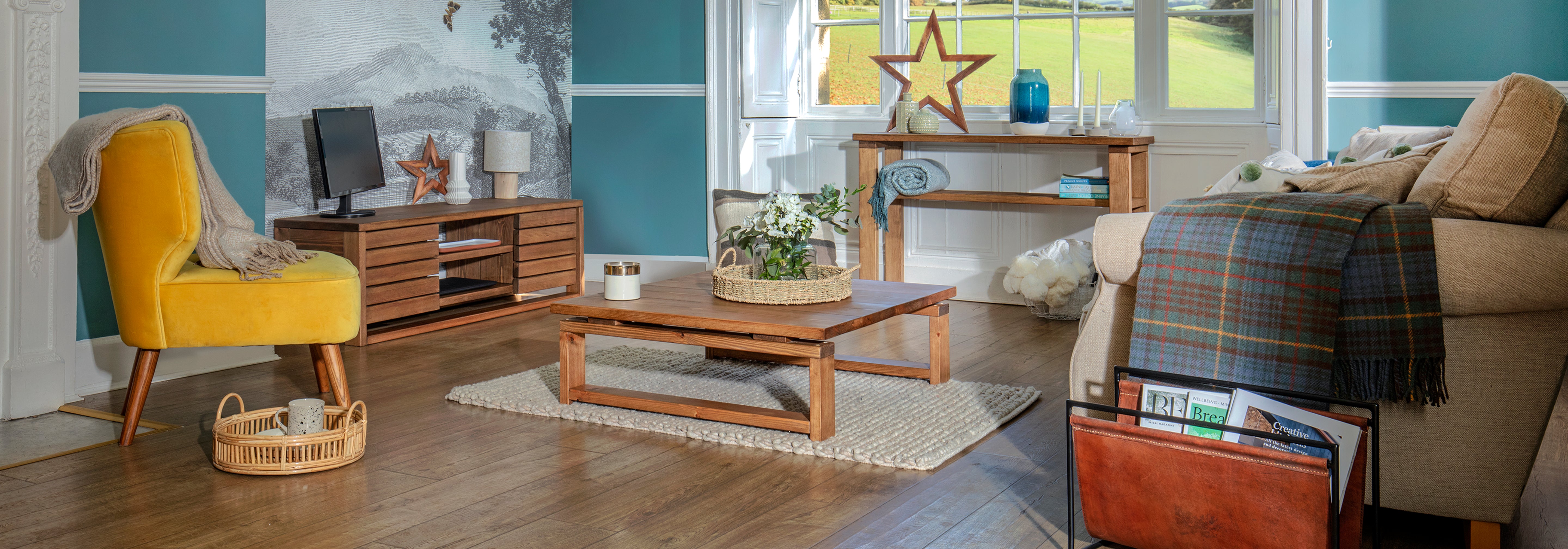 wooden floored country style living room with a bright yellow velvet chair and wooden furniture with a scandinavian style, square legs.